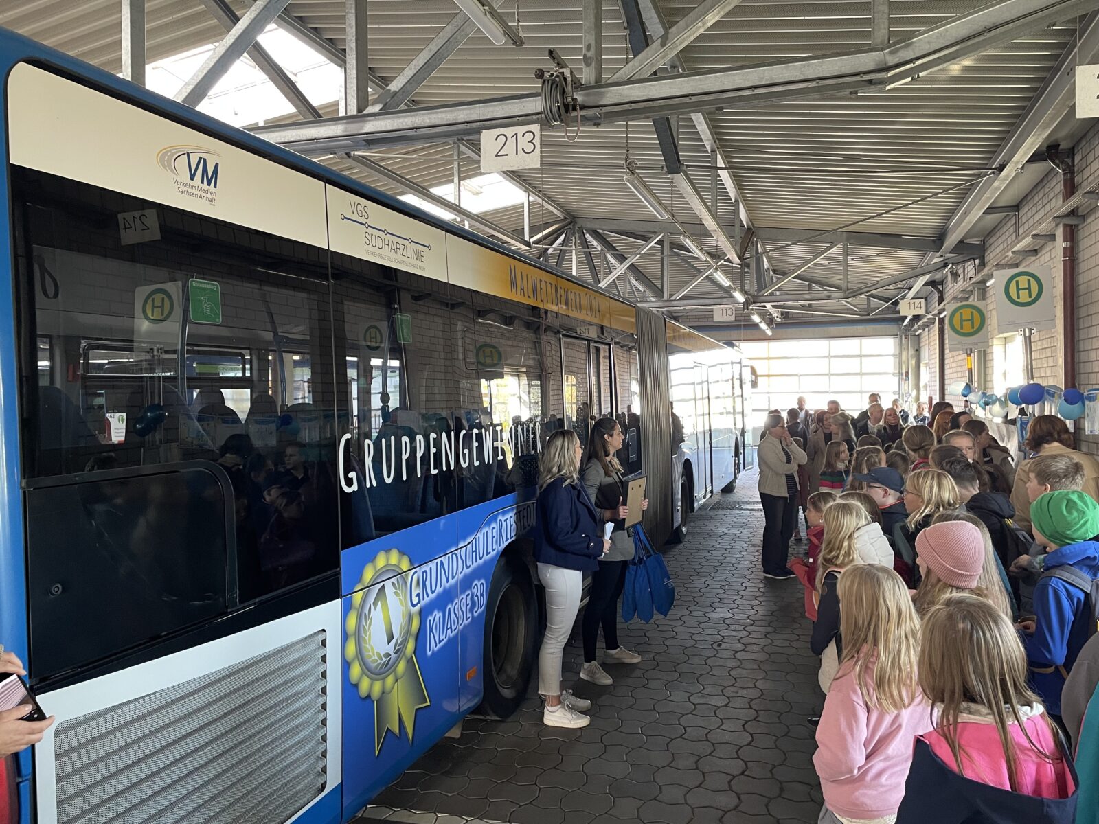 Gruppe von Menschen bei einer Preisverleihung vor einem Bus 
