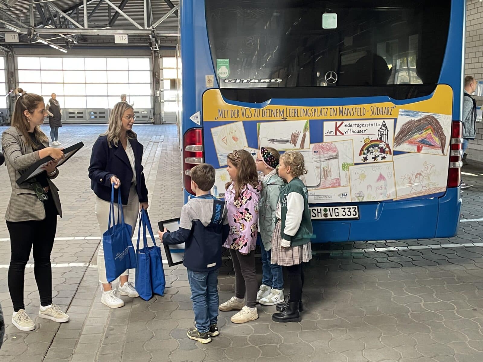 Kinder stehen hinter einem Bus und bekommen Geschenke