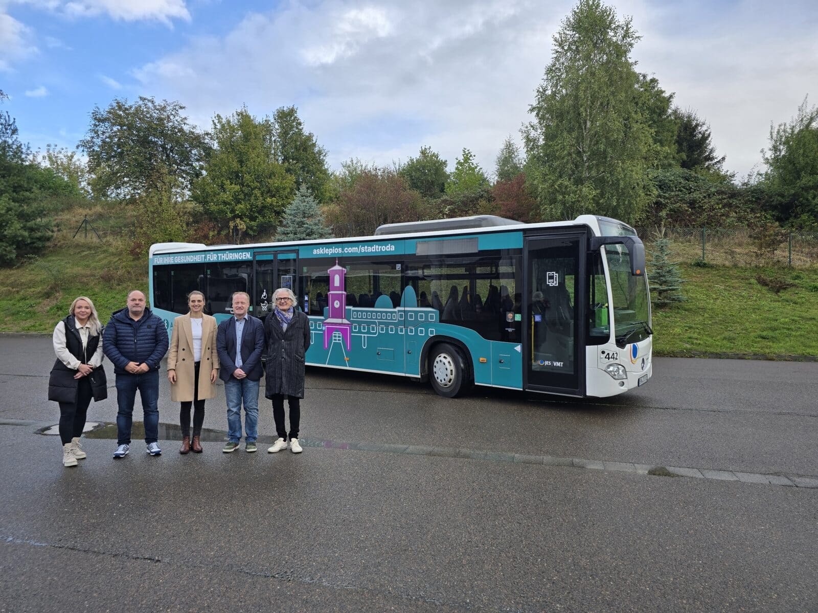 Fünf Personen stehen vor einem blauen Bus