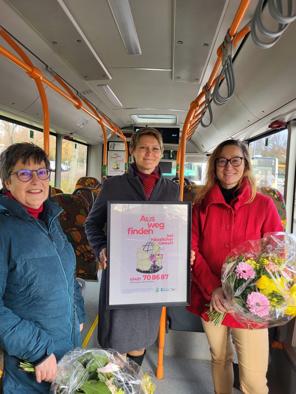 Drei Frauen stehen mit einem Blumenstrauß im Bus 