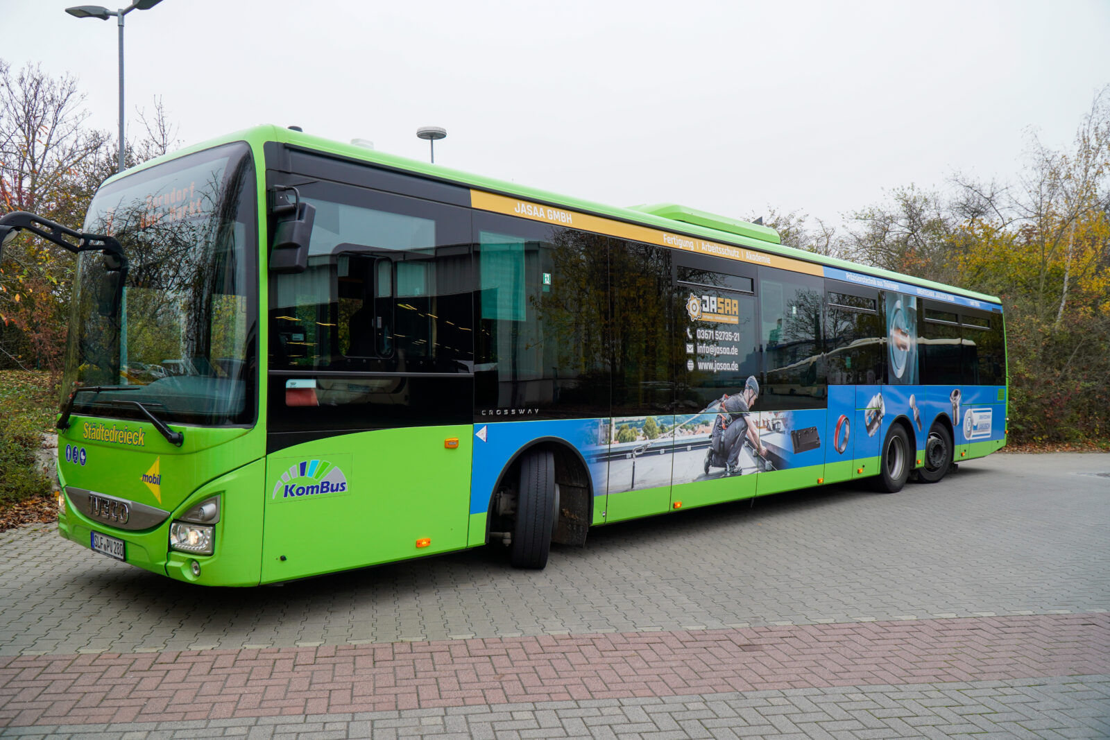 Vorderansicht eines grün-blauen Busses des Unternehmens JASAA. 