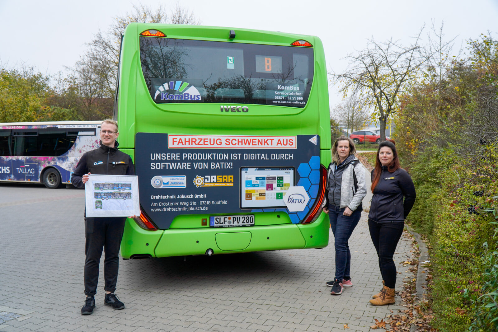 Drei Personen stehen am Heck eines grünen Busses