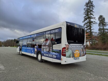 Seiten- und Heckansicht eines blau-weißen Busses welcher auf einem Parkplatz steht