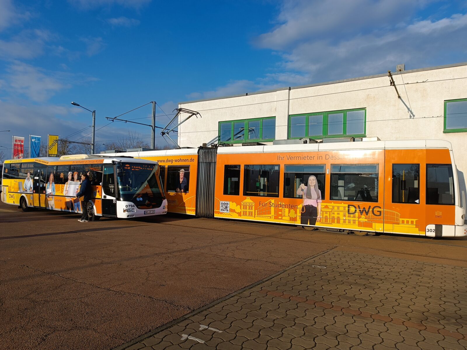 eine orange Straßenbahn und ein oranger Bus stehen nebeneinander